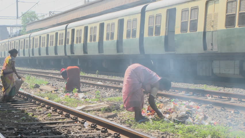 INDIA - CIRCA 2010: Women set fire to small rubbish piles close by railroad tracks circa 2010 in India. Water supply and sanitation in India continue to be inadequate, despite longstanding efforts by the various levels of government and communities at imp