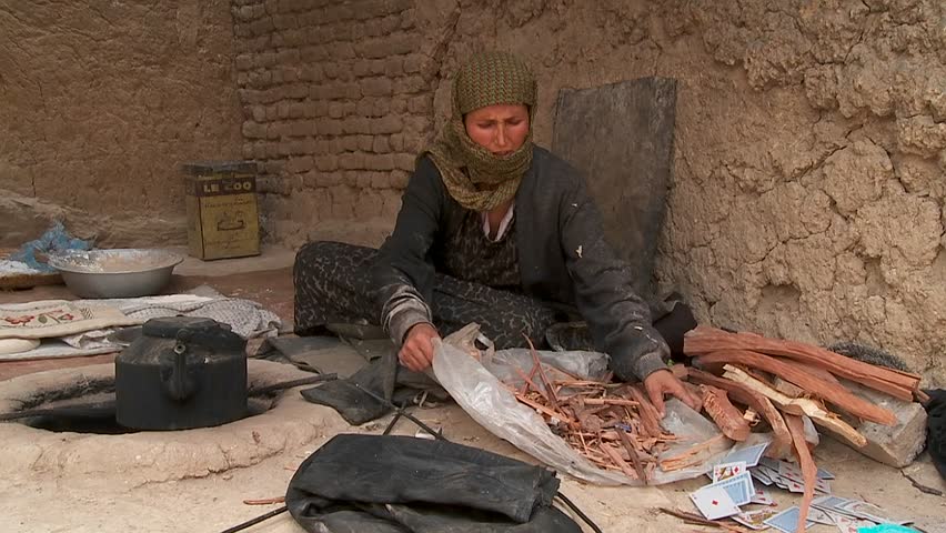 KABUL, AFGHANISTAN - CIRCA 2009: A woman puts wood into a tandoor oven circa 2009 in Kabul, Afghanistan. Afghanistan is an impoverished and least developed country, one of the world's poorest.