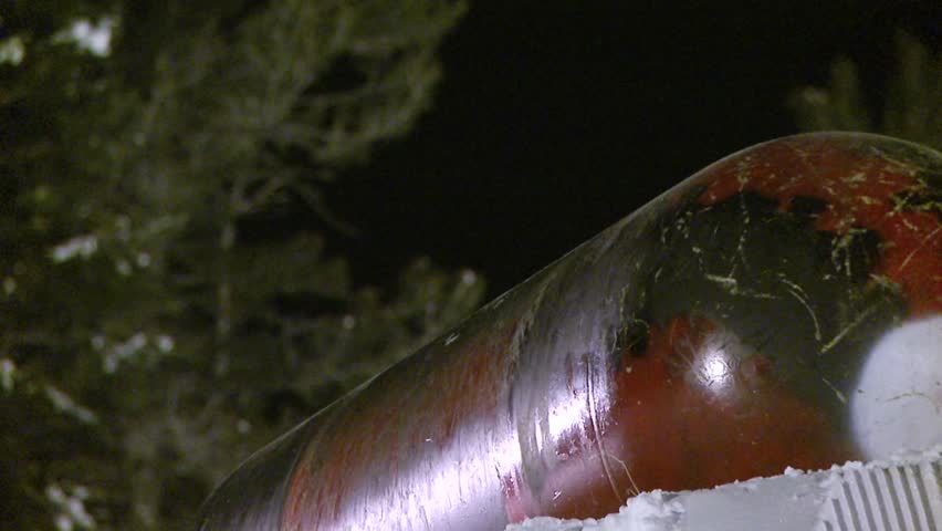 Snowboarder slides across metal cylinder