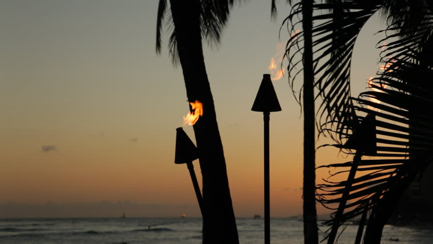 Three tiki torch flames blowing in the wind shortly after sunset on Waikiki Beach in Honolulu on Oahu, Hawaii.