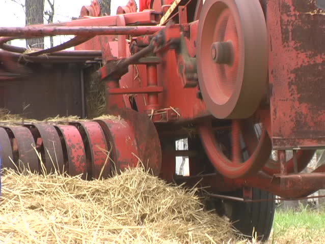 Old Model Square Hay Baler Operating And Being Fed While Stationary 
