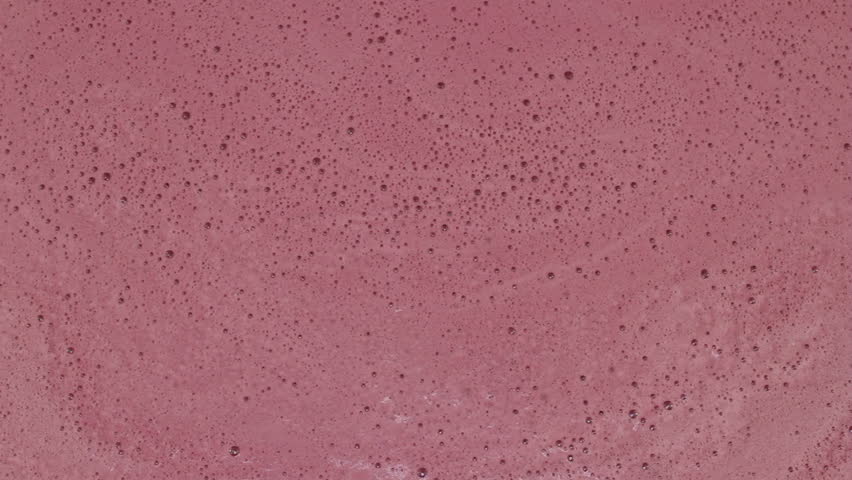 Close-up of blueberry juice bubbles popping on top of organic blueberry juice.