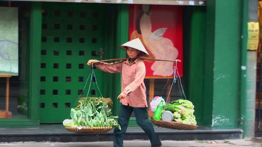 VIETNAM - CIRCA 2009: A woman carries a heavy balanced basket along the street circa 2009 in Vietnam.