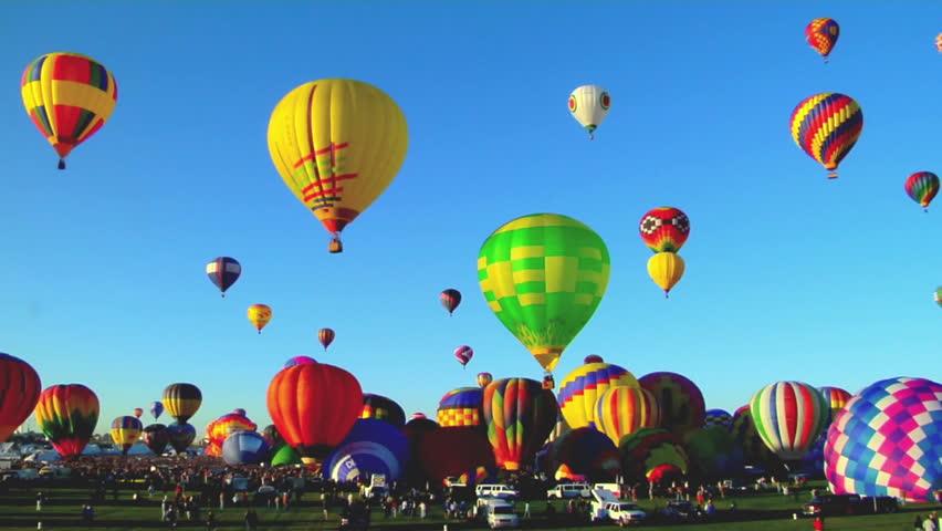 Hot air balloons ascend into the sky from the parking lot