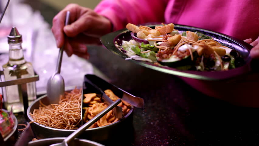 Putting items on salad at bar