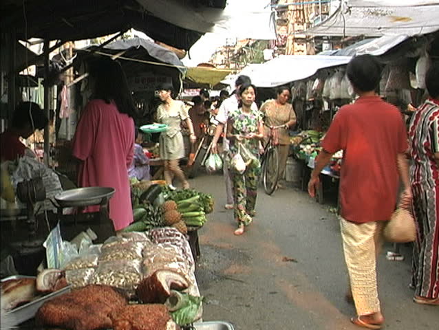 HANOI - CIRCA APRIL 1998: Unidentified people in a narrow passage through a market with a family on a motor scooter in Hanoi. 
