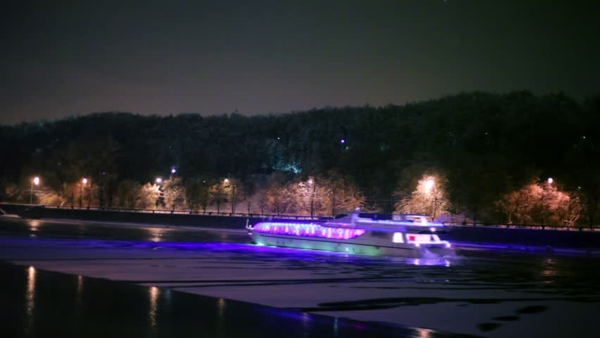 Motor ship decorated with garlands, floats down the river at winter night
