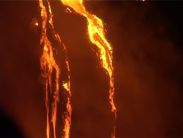 A waterfall of molten lava  trickles down a steep slope during a volcanic  eruption.