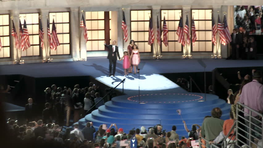 DENVER, COLORADO - CIRCA 2008: Zoom out from Presidential Nominee Barack Obama and his family as a packed Invesco Field claps, cheers and waves flags at the end of the 2008 Democratic National Convention.