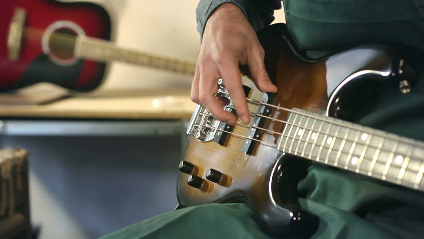 Artisan in workshop playing and testing new guitars and musical instruments. Close-up