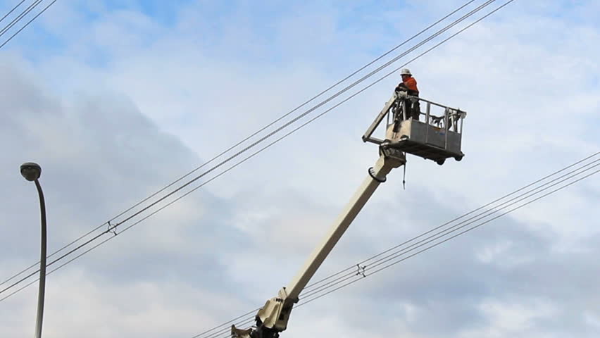 A hydro worker finished up a job and swings his bucket around to the waiting truck below.