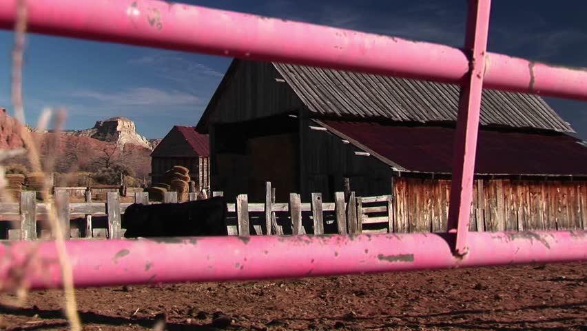 Panning up through foreground of fence of rural Utah ranch house and farm.
