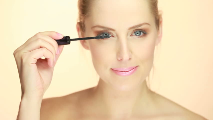 Portrait Of Blue-eyed Blonde Woman applying Mascara
