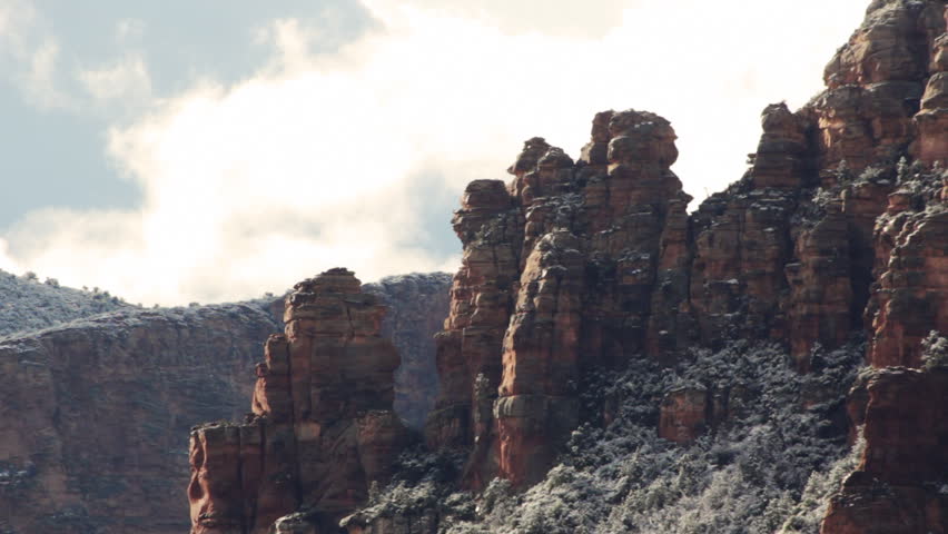 Centuries old spires of red rock coated in a fine layer of snow after the first snow of the season. Clouds move slowly by in the background as the morning sunlight plays with the highlights.