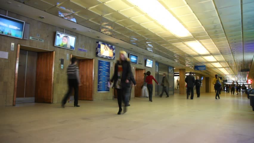 People go on long hall near to lifts and TVs over them