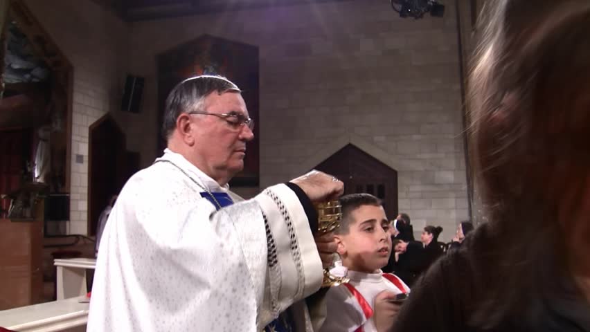 NAZARETH, ISRAEL - DEC 24, 2008: A priest administers communion at the Basilica of Annunciation on December 24, 2008 in Nazareth.
