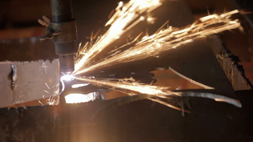 Plasma cutter slicing through hard steel plate, closeup. Cutting a decoration or part used in industry. Sparks and molten metal from automatic machine. Industrial equipment. 