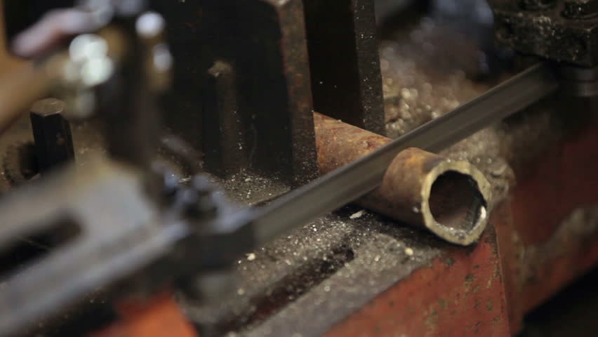 Cutting a hard steel pipe held in vise by heavy duty band saw. Industrial manufacture. Part 2. 