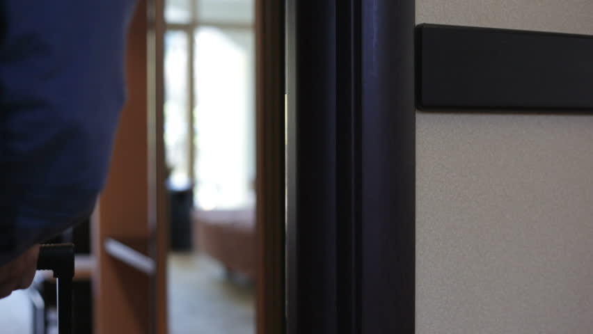 Traveler opens hotel door with a card key, steps inside the room, goes out. 