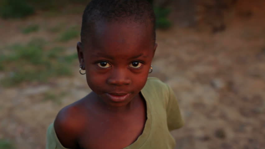 KENYA, AFRICA - CIRCA 2011: A little girl wearing an oversized shirt looking at the camera.