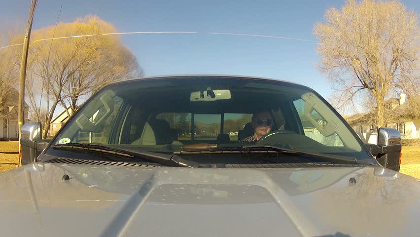 Driving a pickup truck with view from camera looking back at front window. Drive through small country town or village. 