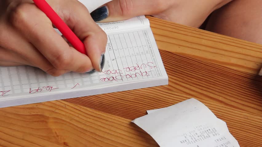 Woman writes notes on checkbook from receipts