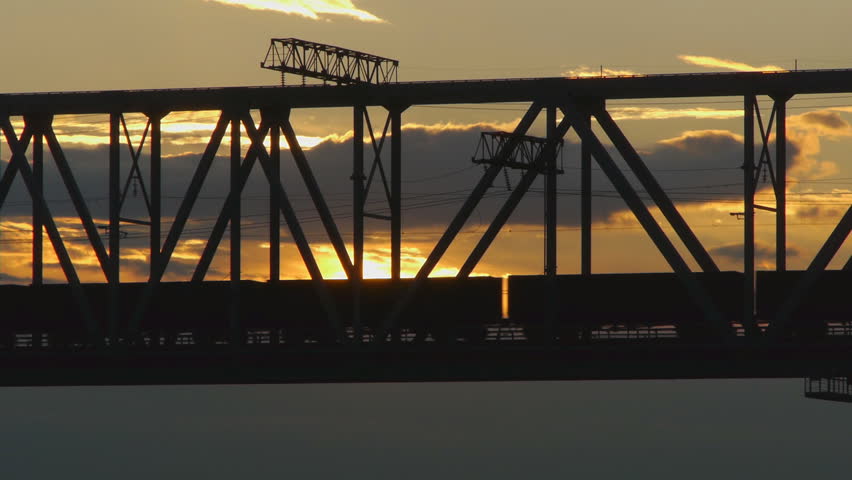 freight train rides on the railway bridge at sunset