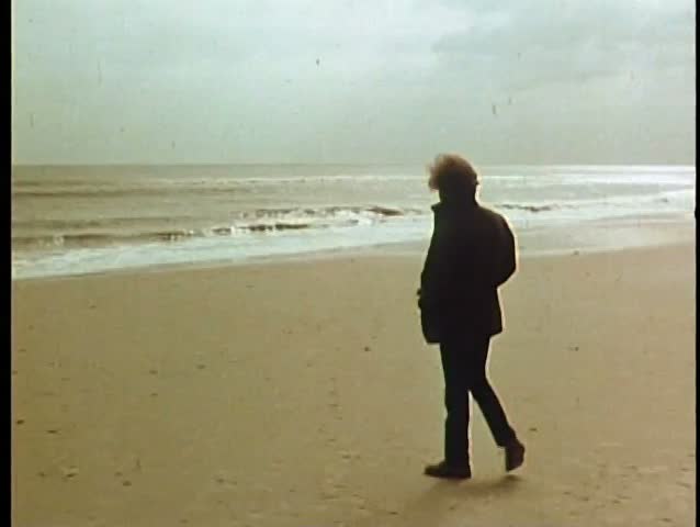 Long shot of man walking  on beach
