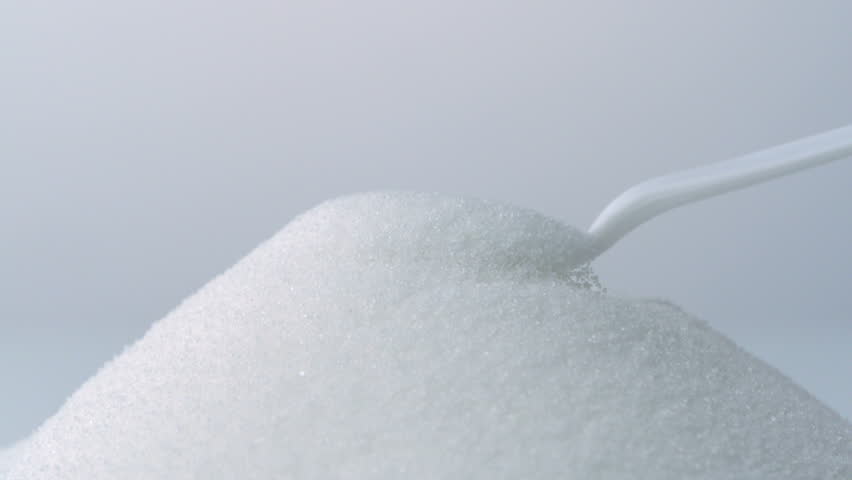 White spoon scoops up sugar