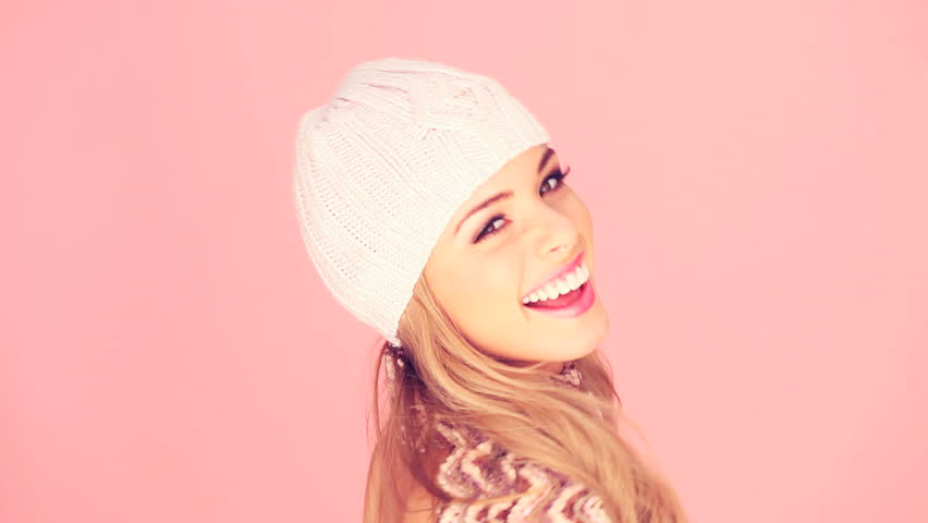Seductive Blond In Winter Outfit with beautiful smile facing out of frame with copyspace on pink.