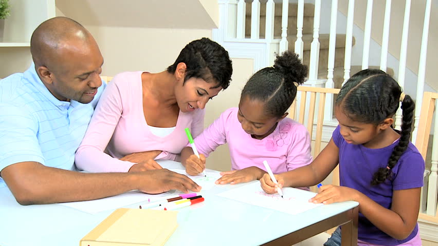 Young ethnic parents watching their young daughters using coloring crayons