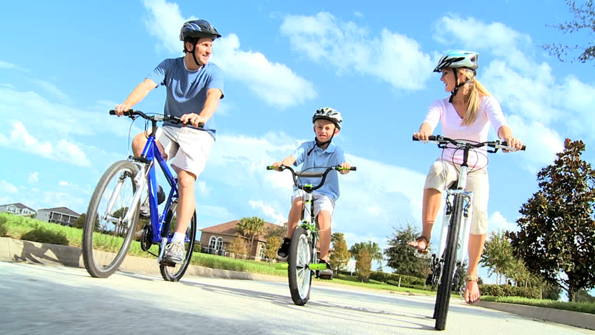 Healthy young caucasian family outdoors together riding their bicycles