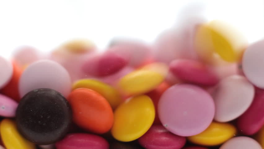 Candy pouring to fill the frame with colourful candy coated chocolates.