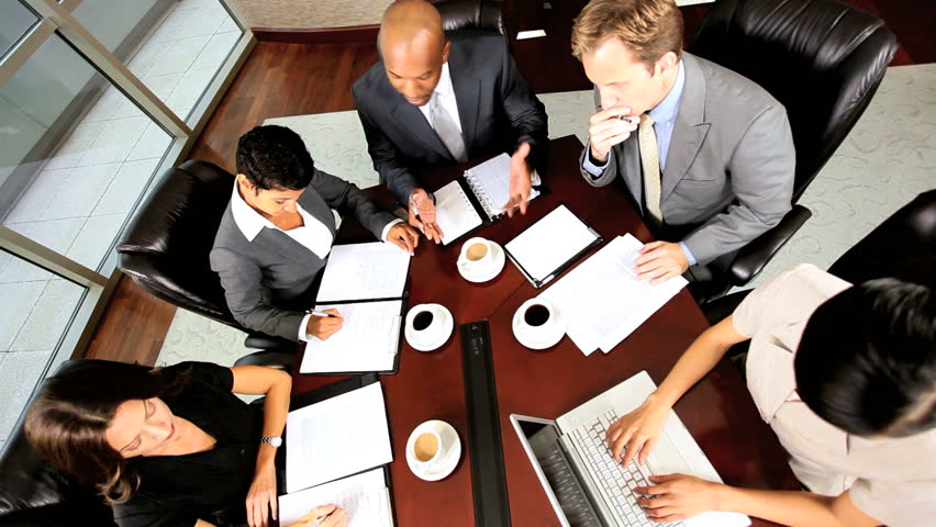 Overhead shot of multi ethnic business executives being motivated by their team leader in a boardroom meeting