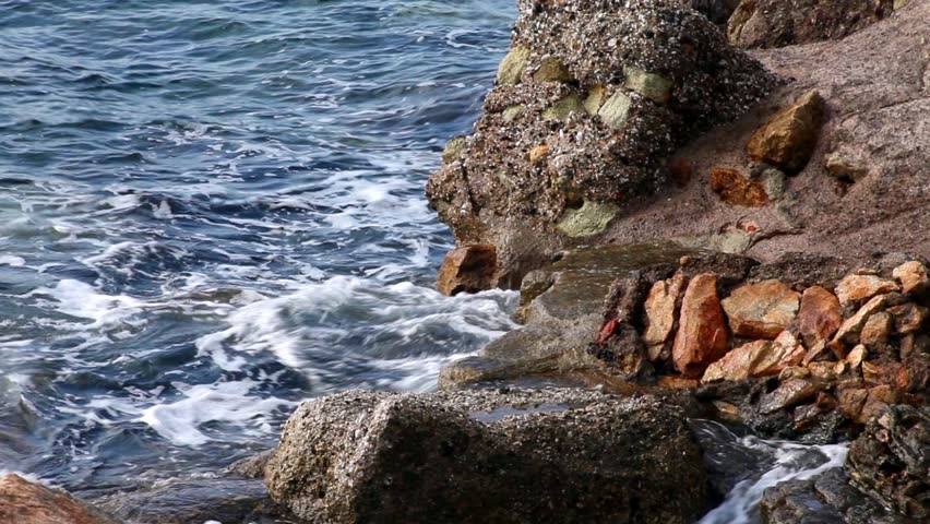 waves splashing on the red rocks, Porto Azzurro, Elba Island, Italy.