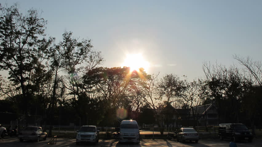 Sunset behind the trees at car park time-lapse
