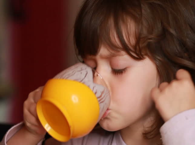 Little girl drinking yoghurt or milk. Slow motion