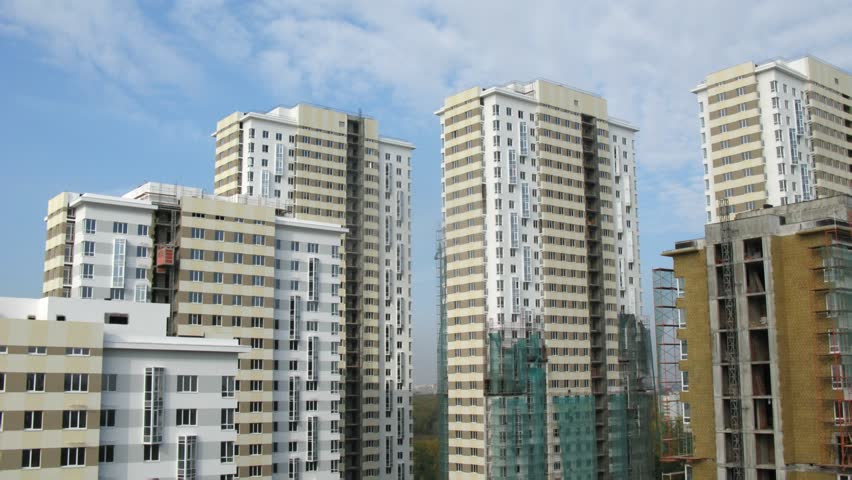Clouds in blue sky float above considerable quantity of new buildings, time lapse