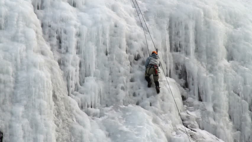 Man ice climb steep high mountain frozen waterfall ice in Utah. Winter recreation and sports in nature.