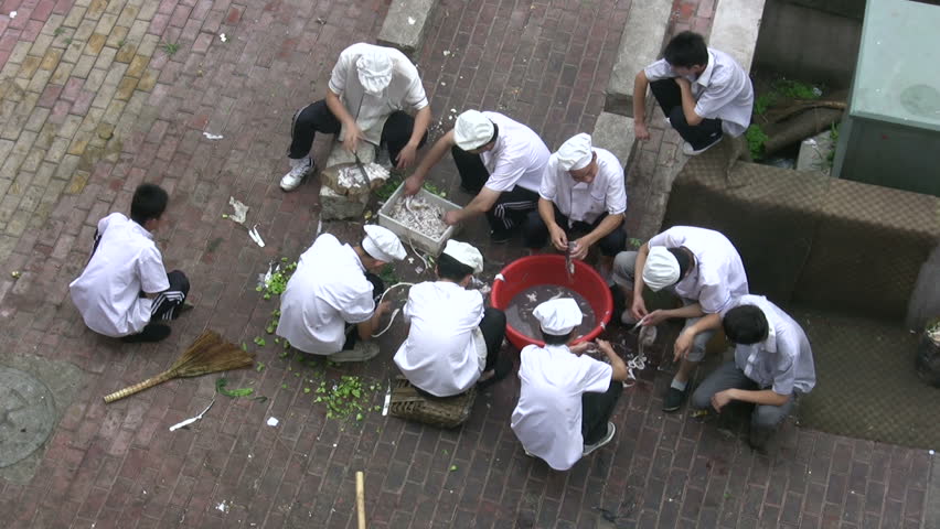 Chinese cooks are preparing for a work day at the back of a restaurant in Qingdao