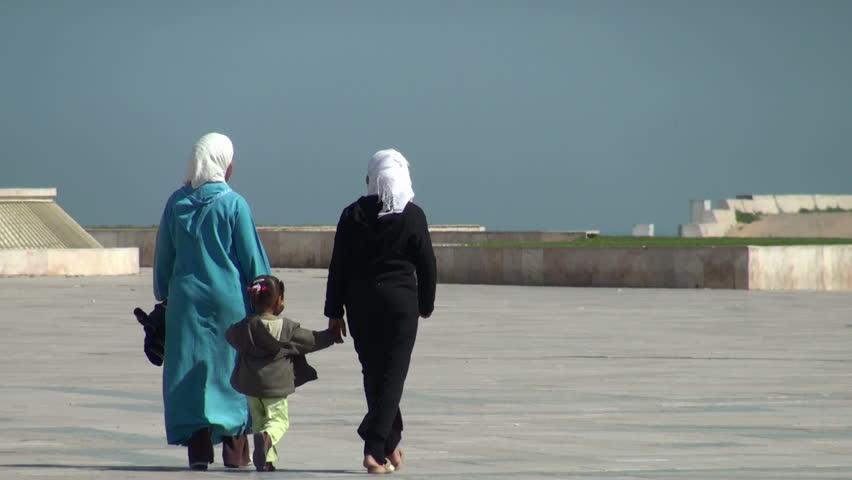Two Muslim women and a little girl are walking on a square near Hassan II Mosque on March 12 2011: the girl leaves the hand and runs forward