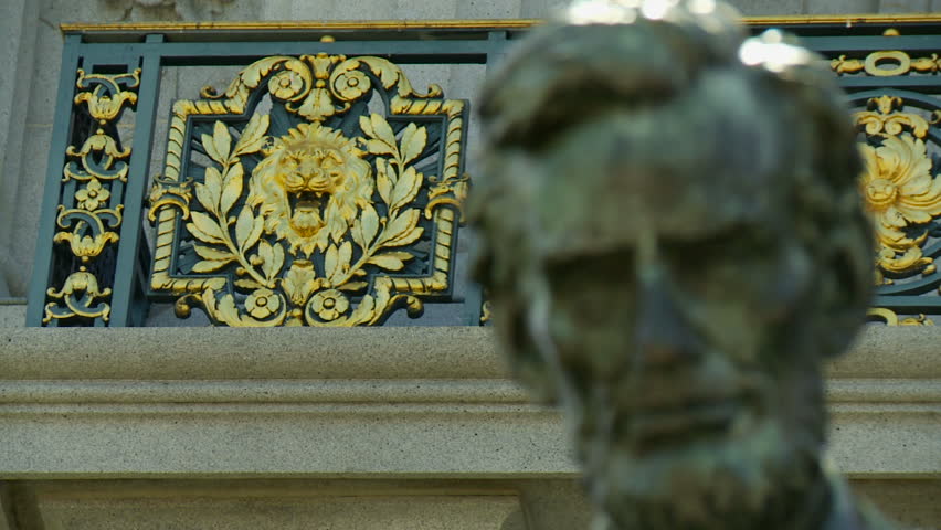 Rack focus from gold lion's head to Abraham Lincoln statue.