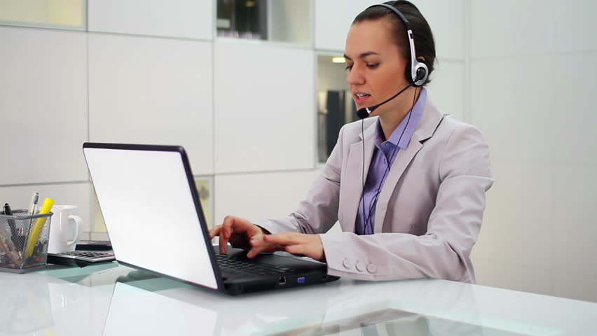 Attractive helpdesk consultant talking on headset in modern office
