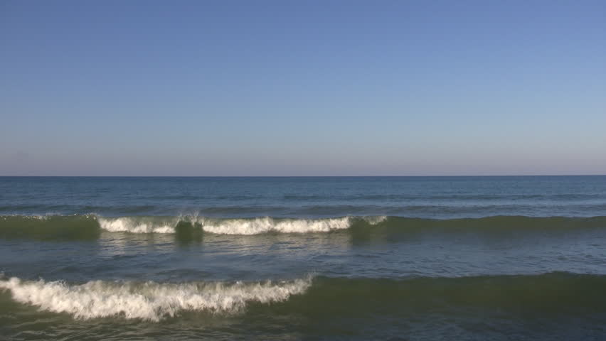 Waves continuously crash all along the beach as the water illuminates the surf.  (High Definition)