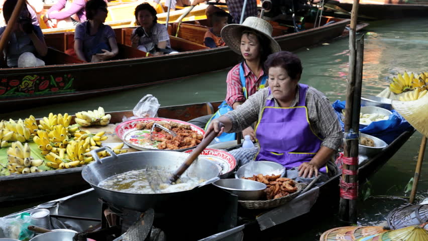 DAMNOEN SADUAK, THAILAND - FEBRUARY 25, 2012: Two women are selling food in Damnoen Saduak Floating Market on February 25, 2012 in Damnoen Saduak, Thailand. 