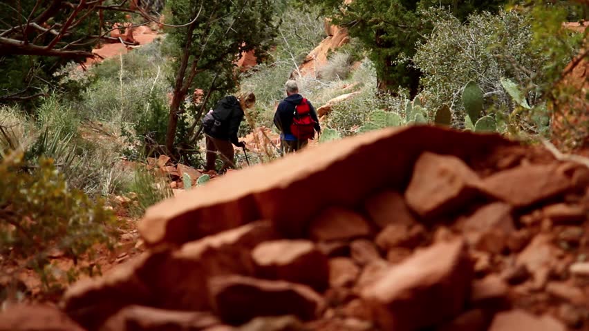 Two unrecognizable hikers explore a canyon trail.