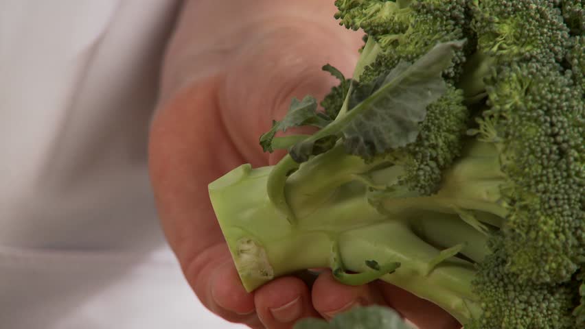 Leaves being removed from broccoli and the florets being cut off