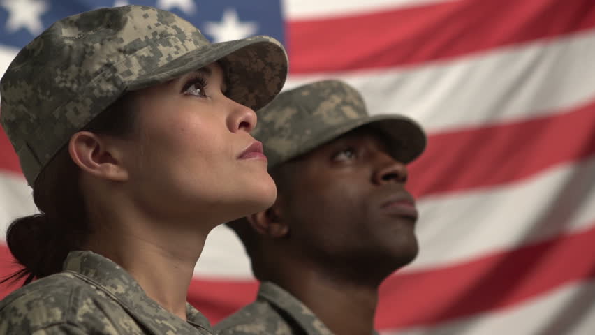 Two U.S. soldiers looking up in front of the flag
