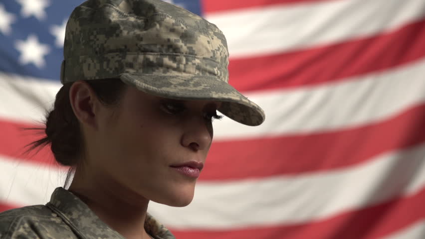Female Soldier in front of flag, looking up