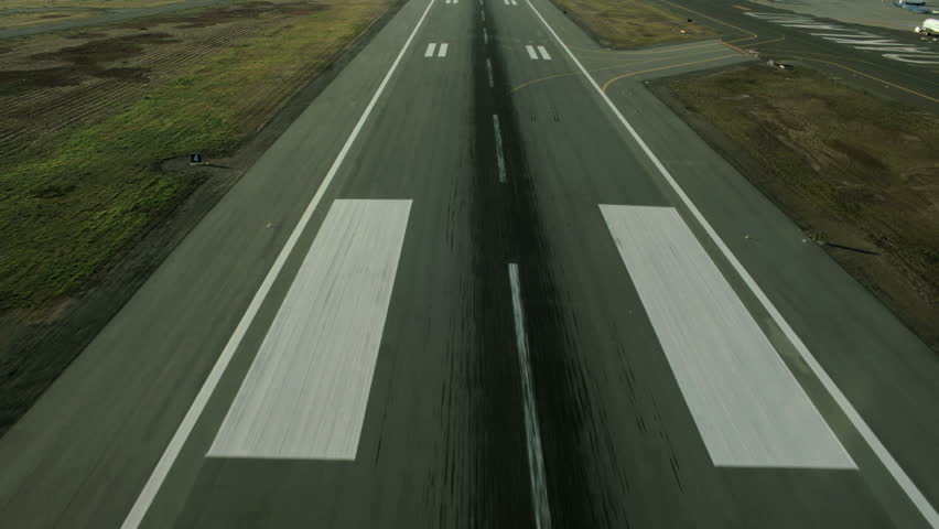 Aerial view of a plane making an approach to landing on an airport runway
